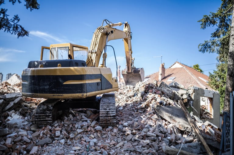 An excavator is actively clearing debris from a recently demolished structure